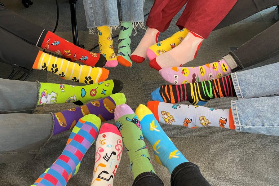 People&apos;s feet in a circle wearing colorful&comma; multi-patterned and mismatched socks&period;