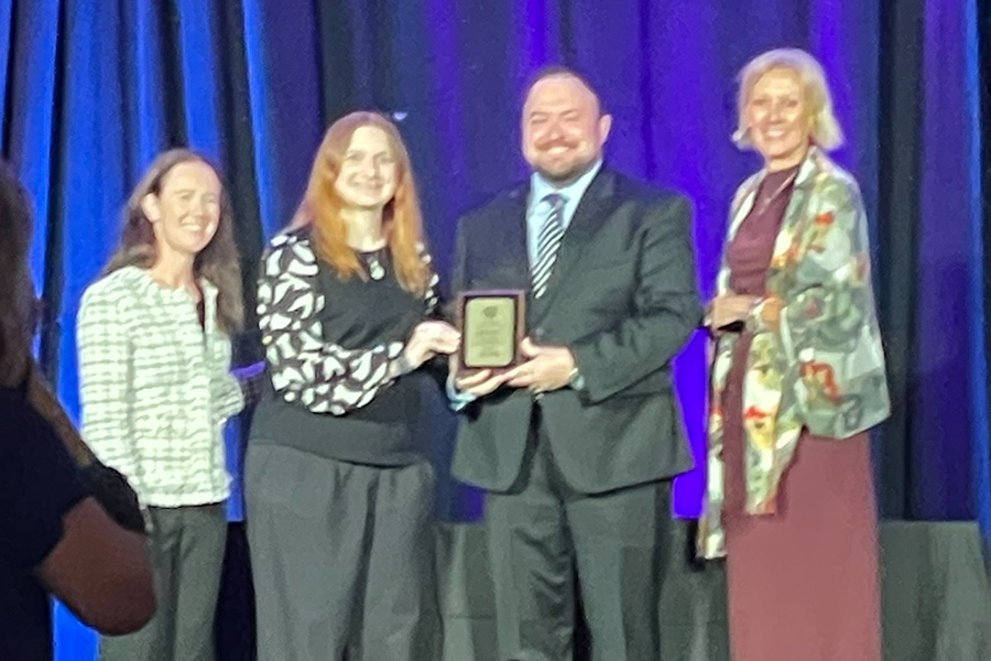 Kate Wampler, Jesse Umbra, Chritopher Smith, and Kim Michael pose holding their award plaque.