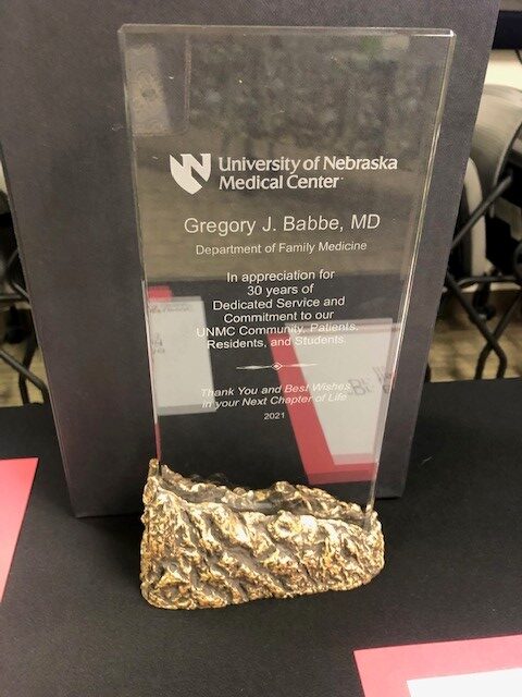 A clear plaque with "University of Nebraska Medical Center" and "Gregory J. Babbe, MD" text is set on a textured gold stand. It honors 30 years of service.