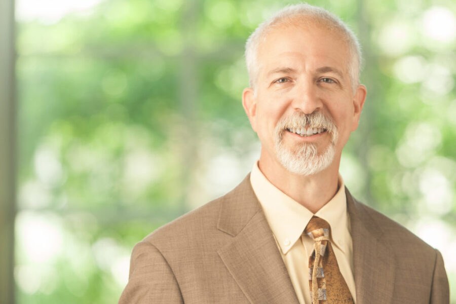 Photo of Dr&period; Mark Rupp wearing tan suit on a green background