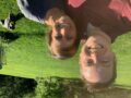 photo of Dr. McElroy and his wife in a green field with their dog in the background behind them
