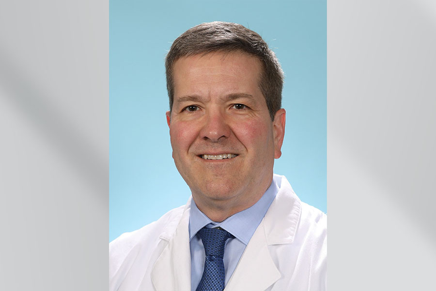 headshot of Dr&period; warren wearing a white coat with a blue collared shirt and blue tie&period; on sky blue background