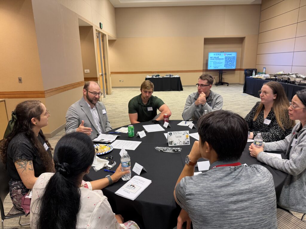 Conference participants engage in a small-group discussion around a table during a professional development event