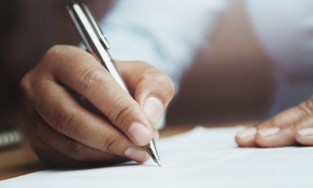 Man writing on paper with silver pen