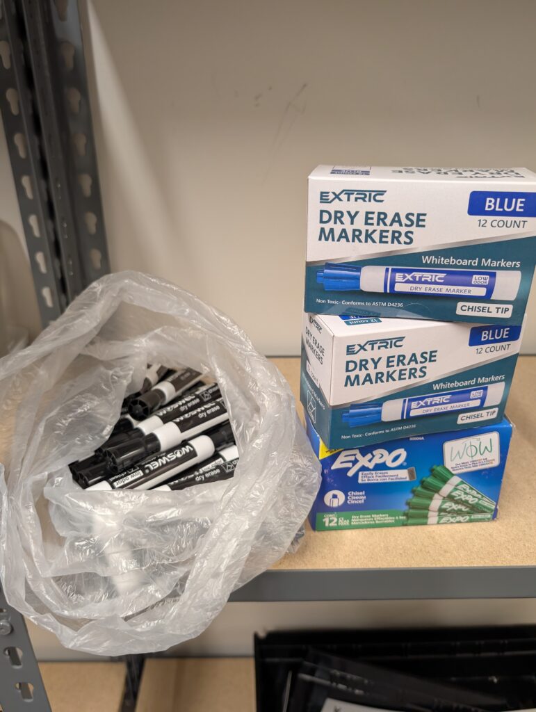 Dry erase markers in boxes and in bag on shelf