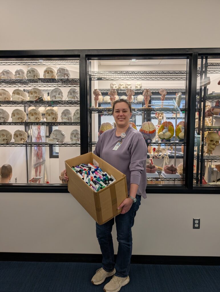 Library staff member holding box of old dry erase markers