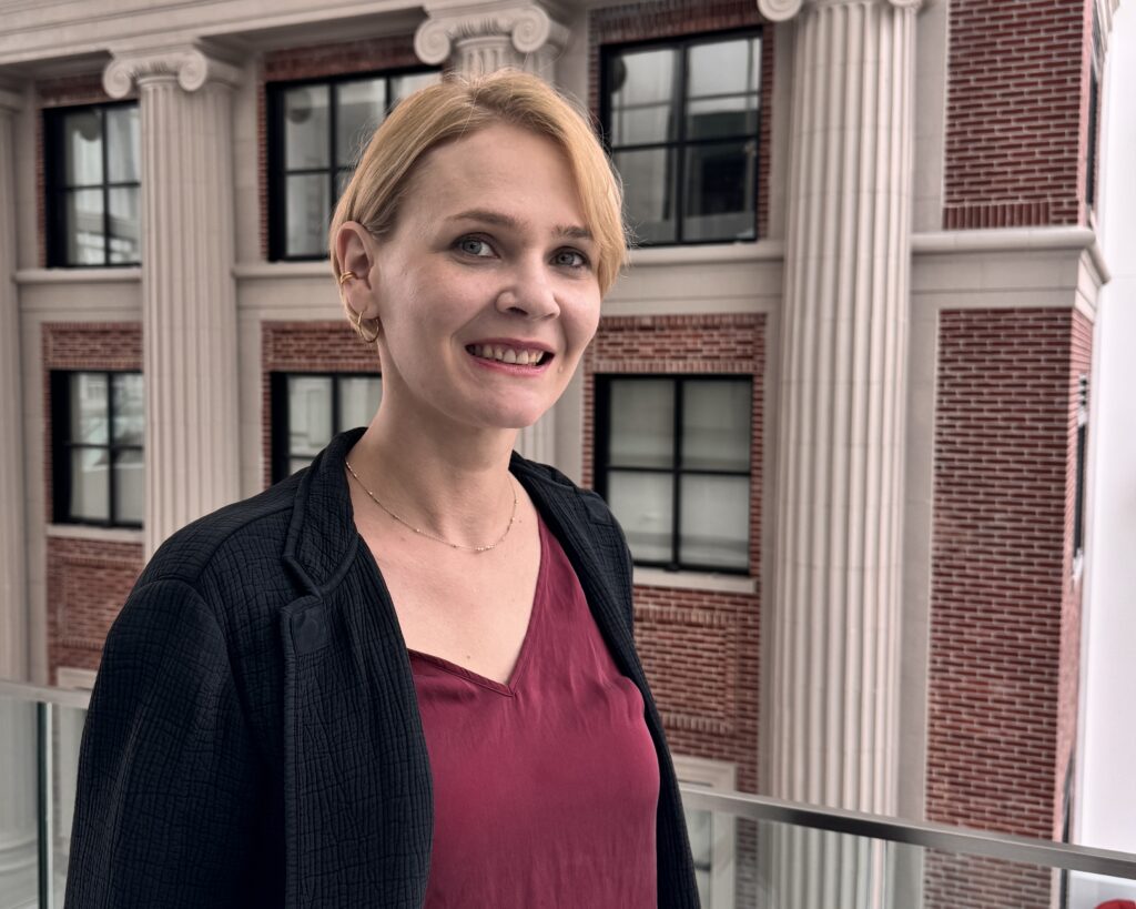 Image of woman in black blazer and maroon shirt.